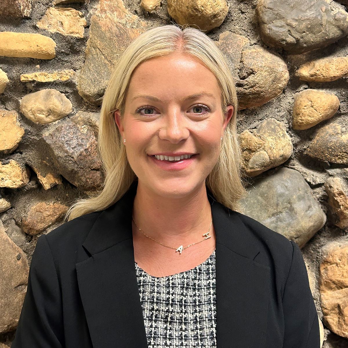 Ali Farmer in front of stone wall.